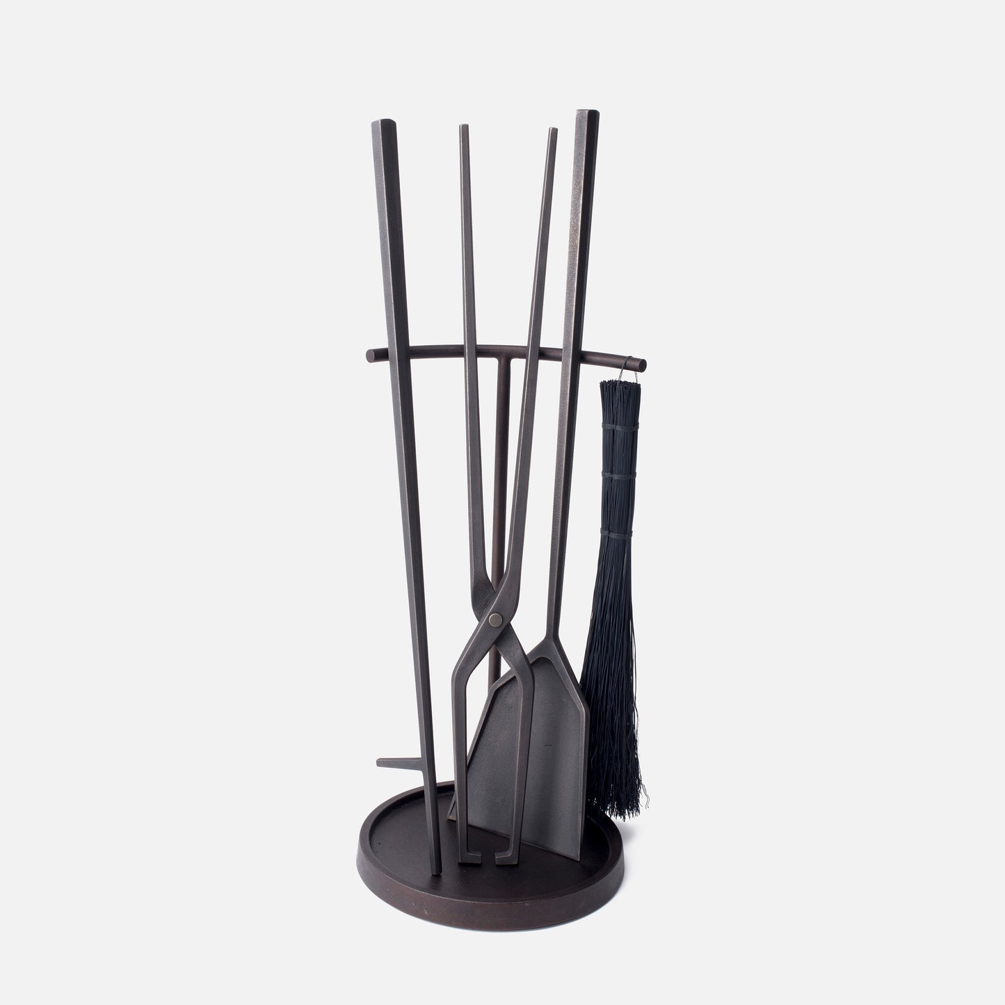 A hearth tool set composed of a poker, shovel, tongs and a brush in a blackened bronze finish.